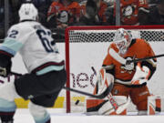 Anaheim Ducks goaltender Lukas Dostal (1) deflects the puck with Seattle Kraken defenseman Brandon Montour (62) watching during the first period of an NHL hockey game in Anaheim, Calif., Monday, Nov. 25, 2024.