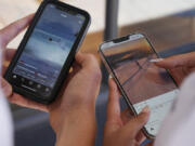 14-year-old Henry, left, and Angel, 15, use their phones to view social media in Sydney, Friday, Nov. 8, 2024.