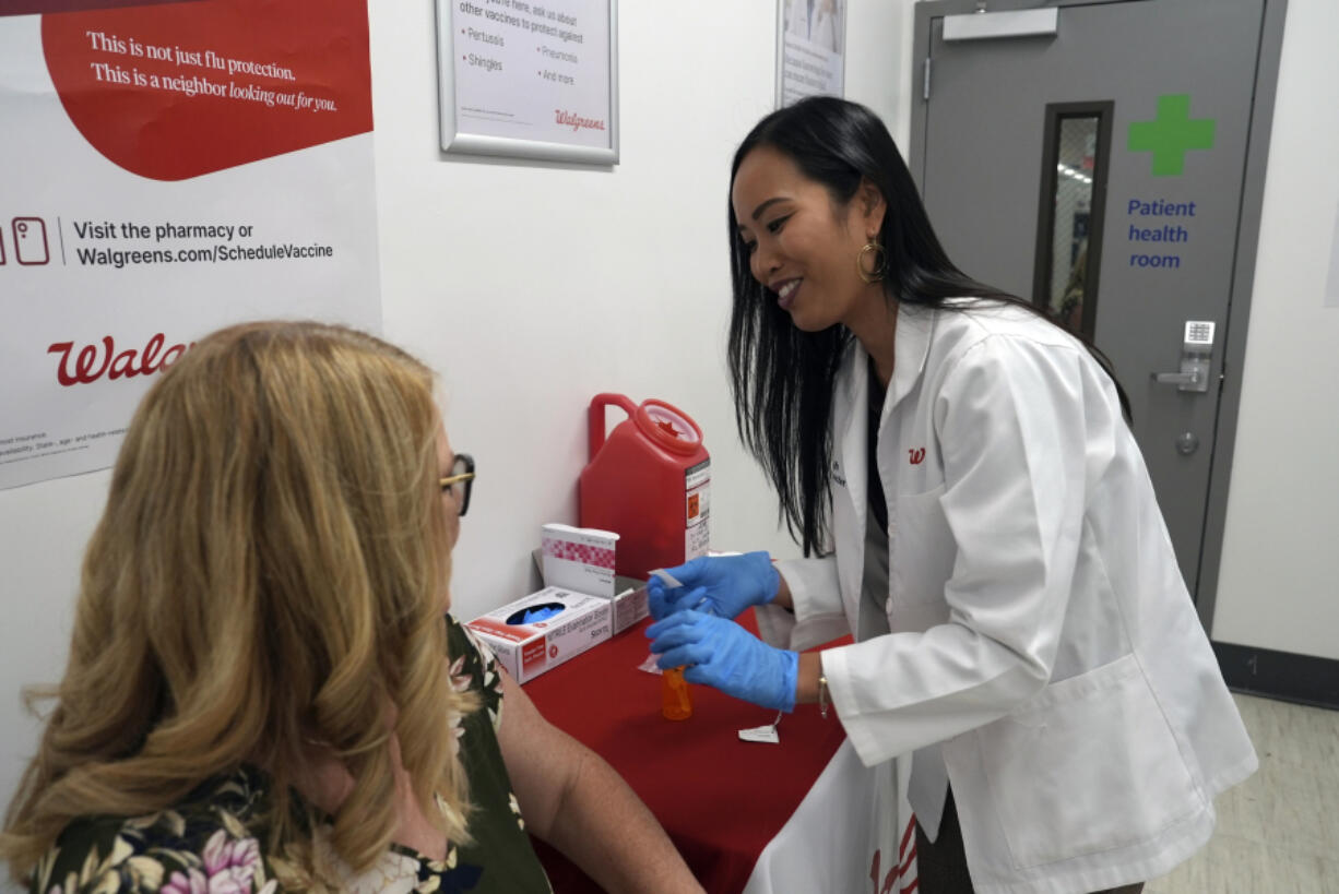 Anh Nguyen prepares to administer a COVID-19 vaccine Sept. 24 for Kelly Vazquez at a pharmacy in New York.