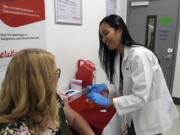 Anh Nguyen prepares to administer a COVID-19 vaccine Sept. 24 for Kelly Vazquez at a pharmacy in New York.