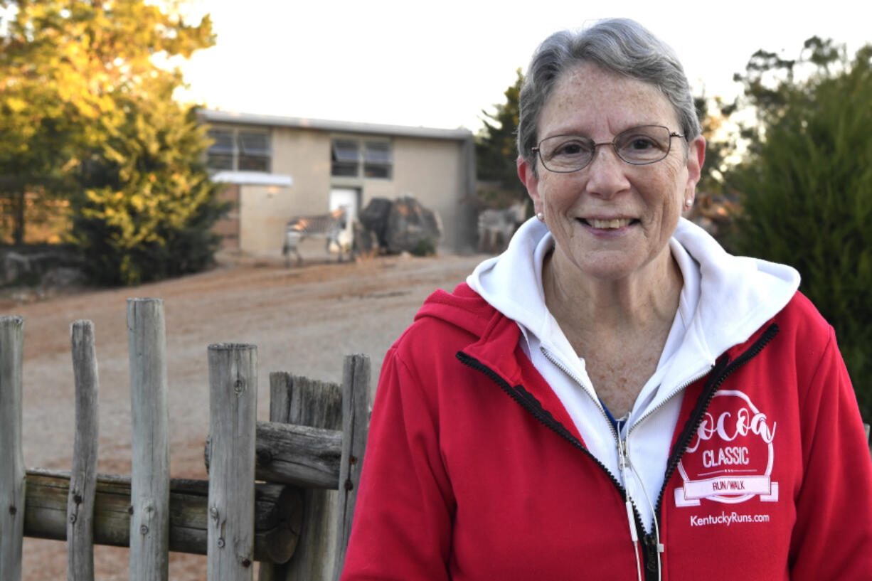 Janet Rapp, a member of the Get Healthy Walking Club stands in front of the zebra enclosure during the early morning at the Louisville Zoo in Louisville, Ky., Friday, Oct. 18, 2024. (AP Photo/Timothy D.