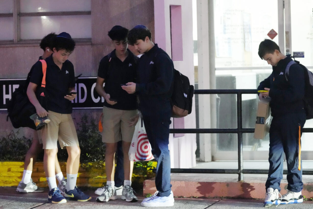 Students wait for their bus to school, Tuesday, Oct. 29, 2024, in Surfside, Fla. Daylight saving time ends at 2 a.m. local time Sunday, Nov. 3. Standard time will last until March 9.