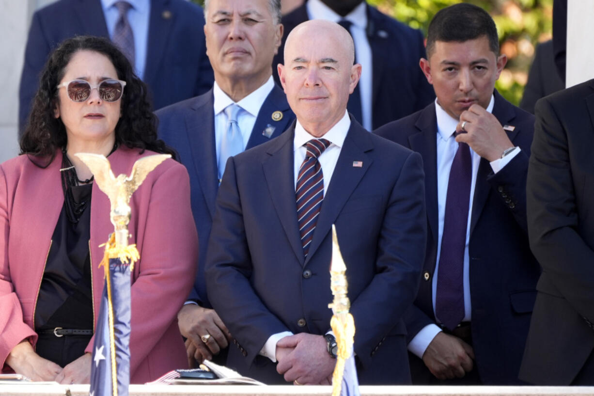 Homeland Security Secretary Alejandro Mayorkas, center, looks on before President Joe Biden speaks at the National Veterans Day Observance at the Memorial Amphitheater at Arlington National Cemetery in Arlington, Va., Monday, Nov. 11, 2024.