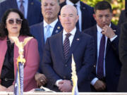 Homeland Security Secretary Alejandro Mayorkas, center, looks on before President Joe Biden speaks at the National Veterans Day Observance at the Memorial Amphitheater at Arlington National Cemetery in Arlington, Va., Monday, Nov. 11, 2024.