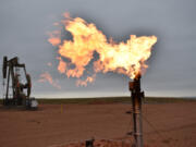 FILE - A flare burns natural gas at an oil well in Watford City, N.D., Aug. 26, 2021.