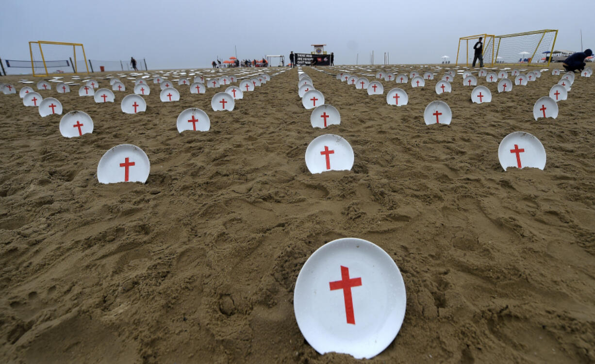 Plates marked with crosses, symbolizing people suffering from hunger worldwide, are displayed at Copacabana Beach during a protest aimed at drawing the attention of leaders attending the upcoming G20 summit in Rio de Janeiro, Saturday, Nov. 16, 2024.