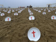 Plates marked with crosses, symbolizing people suffering from hunger worldwide, are displayed at Copacabana Beach during a protest aimed at drawing the attention of leaders attending the upcoming G20 summit in Rio de Janeiro, Saturday, Nov. 16, 2024.