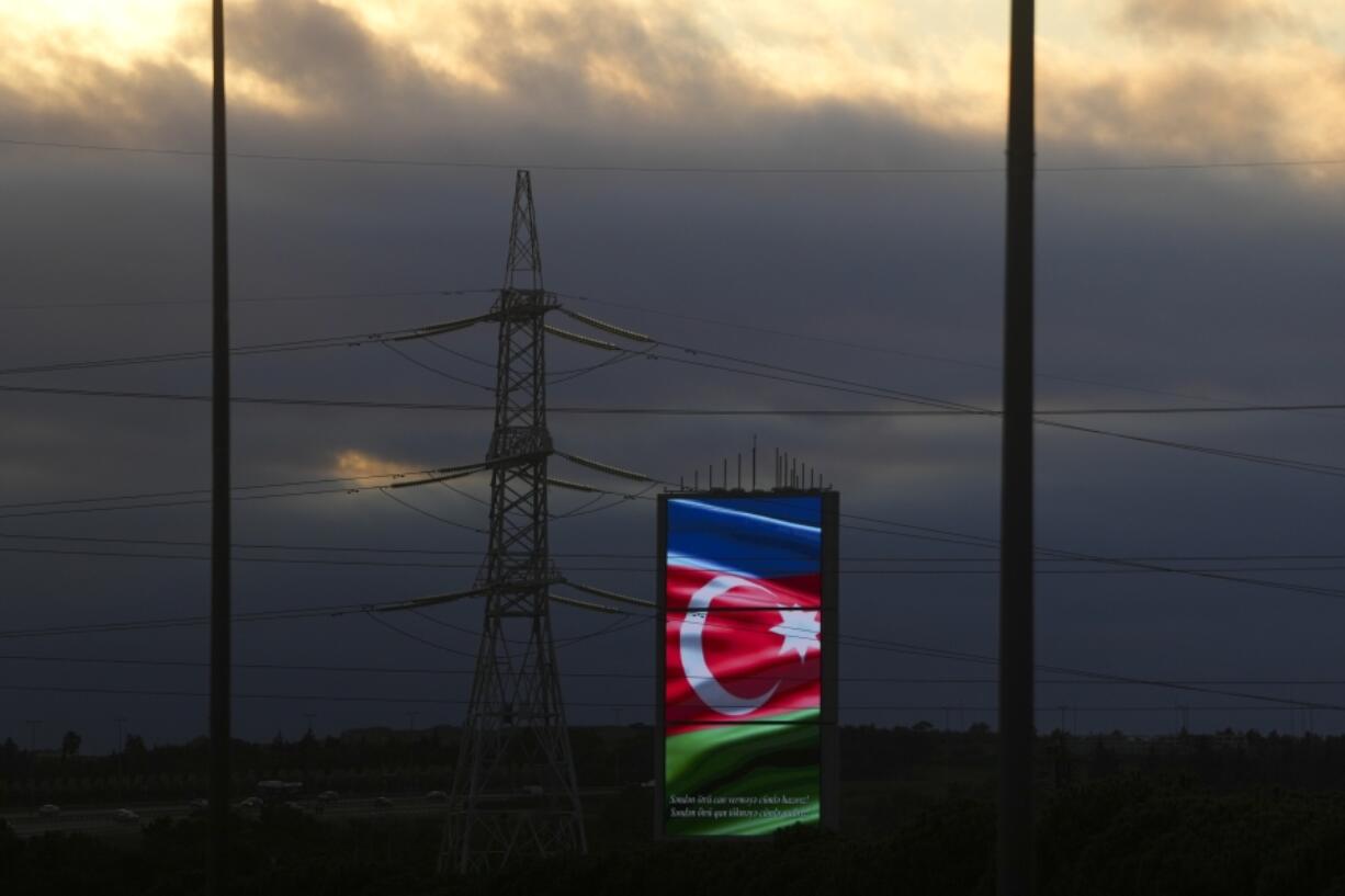 A screen displaying the Azerbaijan flag sits near power lines along a road during the COP29 U.N. Climate Summit, Wednesday, Nov. 13, 2024, in Baku, Azerbaijan.