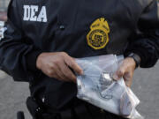 FILE - A DEA agent shows a gun allegedly seized from a suspected drug dealer after his arrest during a raid on a public housing project in Mayaguez, Puerto Rico, July 9, 2010.