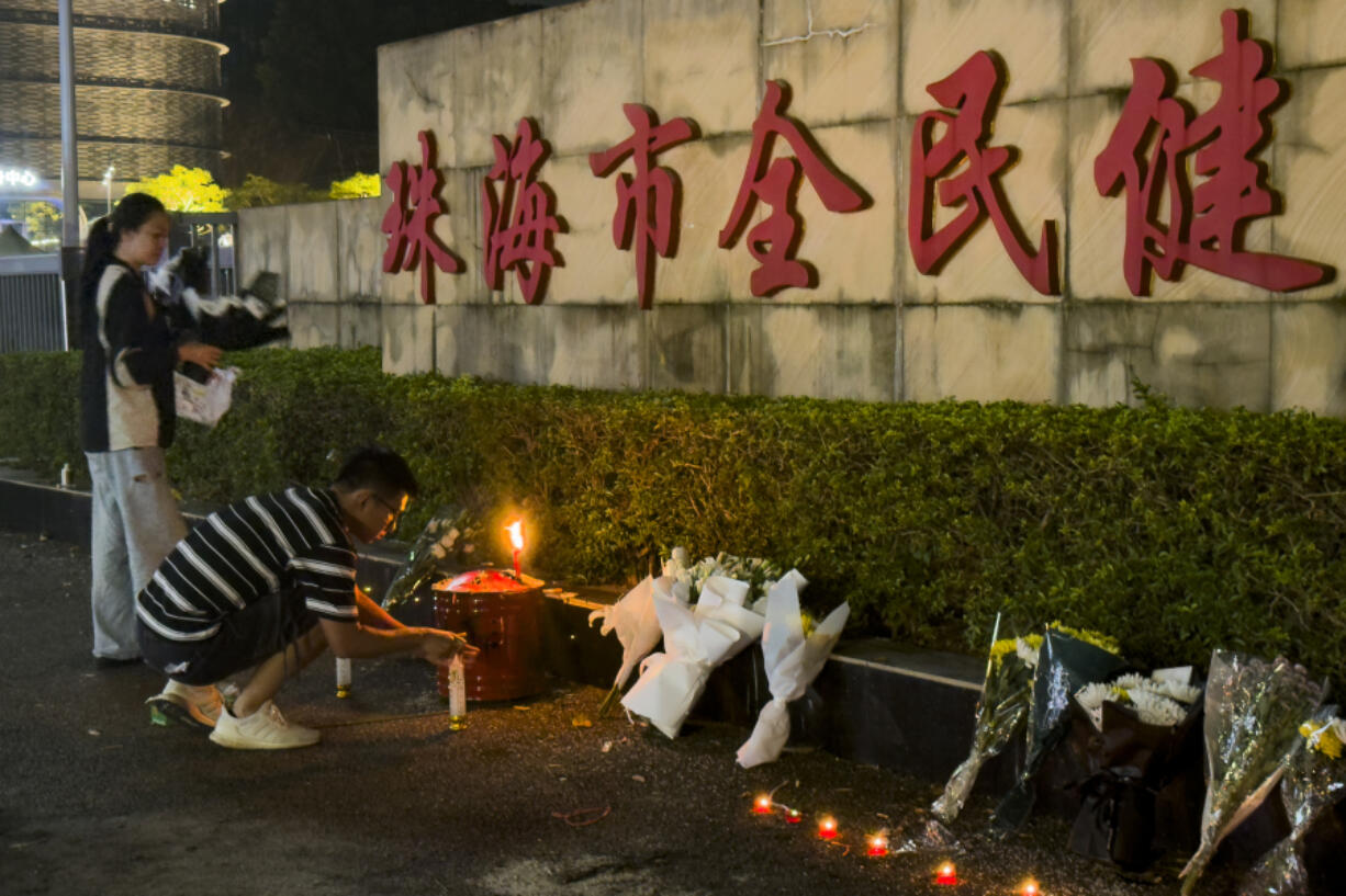 A man lights a candle near flowers placed outside the &ldquo;Zhuhai People&rsquo;s Fitness Plaza&rdquo; where a man deliberately rammed his car into people exercising at the sports center, killing some and injuring others in Zhuhai in southern China&rsquo;s Guangdong province on Tuesday, Nov. 12, 2024.