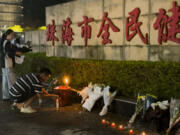 A man lights a candle near flowers placed outside the &ldquo;Zhuhai People&rsquo;s Fitness Plaza&rdquo; where a man deliberately rammed his car into people exercising at the sports center, killing some and injuring others in Zhuhai in southern China&rsquo;s Guangdong province on Tuesday, Nov. 12, 2024.