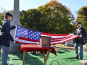 In this photo provided by The Valley Breeze, Civil War re-enactors fold an American flag near an urn, center, containing the cremated remains of Byron R. Johnson, a Union soldier who was born in Pawtucket, R.I., in 1844 and fought in the Civil War, during funeral services, Wednesday, Oct. 16, 2024, at Oak Grove Cemetery, in Pawtucket, after his remains were transferred from storage at a cemetery in Seattle.