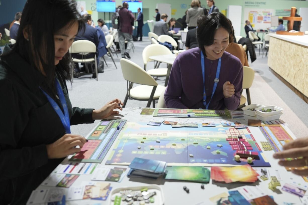 Borami Seo, Solutions for Our Climate, left, and Yi Hyun Kim, Solutions for Our Climate, play Daybreak, a game where players are supposed to work together to find a way to curb climate change, at the COP29 U.N. Climate Summit on Nov. 19 in Baku, Azerbaijan. (Joshua A.