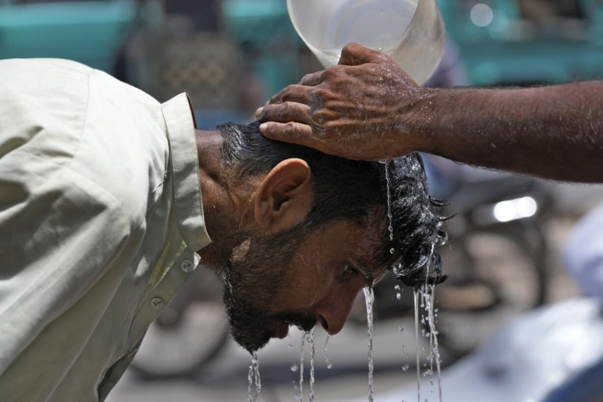 FILE - A volunteer pours water to cool a man off during a hot day in Karachi, Pakistan, May 21, 2024.