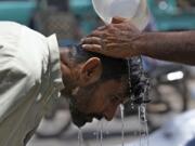 FILE - A volunteer pours water to cool a man off during a hot day in Karachi, Pakistan, May 21, 2024.