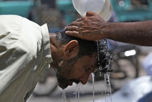 FILE - A volunteer pours water to cool a man off during a hot day in Karachi, Pakistan, May 21, 2024.