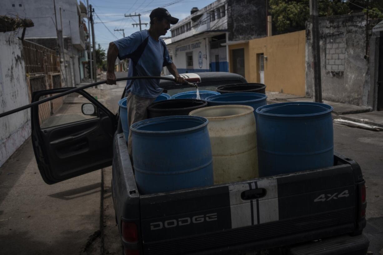 FILE - A man fills containers with water due to the shortage caused by high temperatures and drought in Veracruz, Mexico, on June 16, 2024.