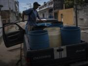 FILE - A man fills containers with water due to the shortage caused by high temperatures and drought in Veracruz, Mexico, on June 16, 2024.