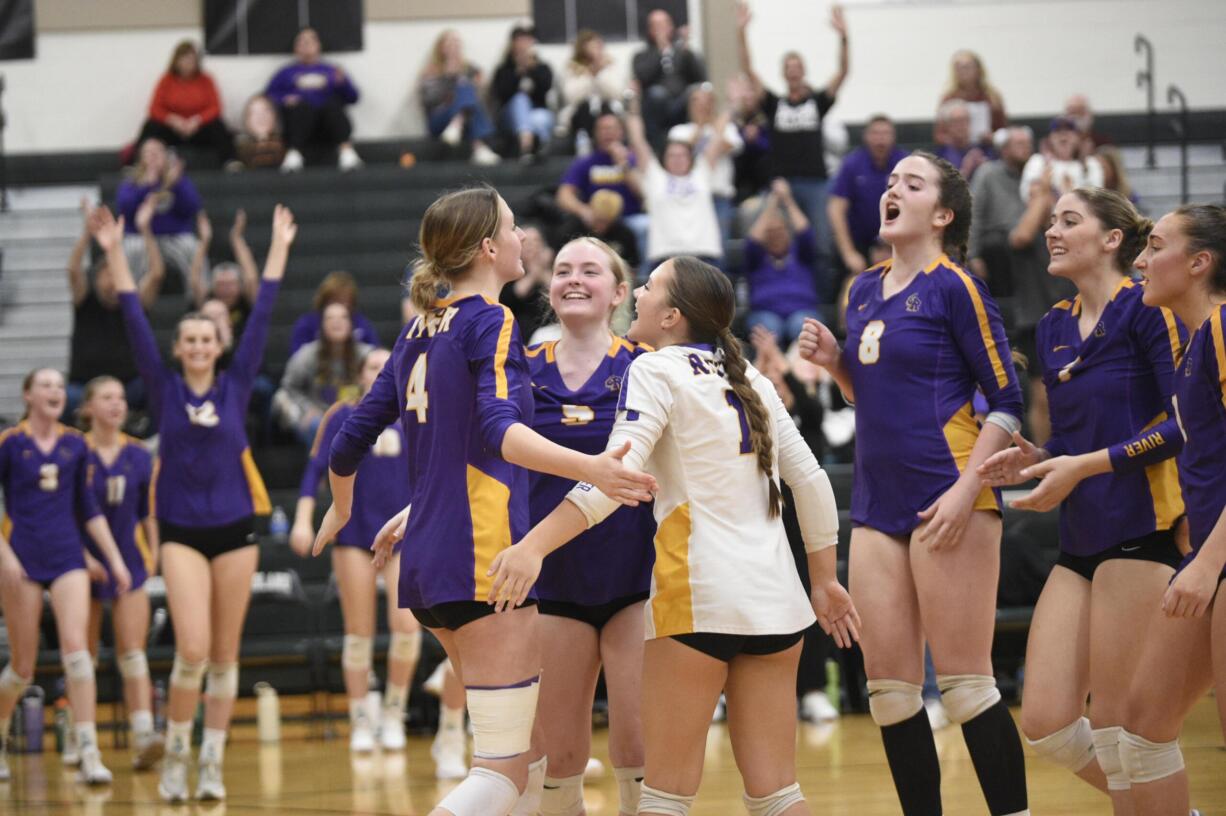 Columbia River players embrace teammate Sydney Dreves (4) after the Rapids won the second set in the Class 2A District 4 volleyball championship against Ridgefield on Saturday, Nov. 9, 2024, at Woodland High School.