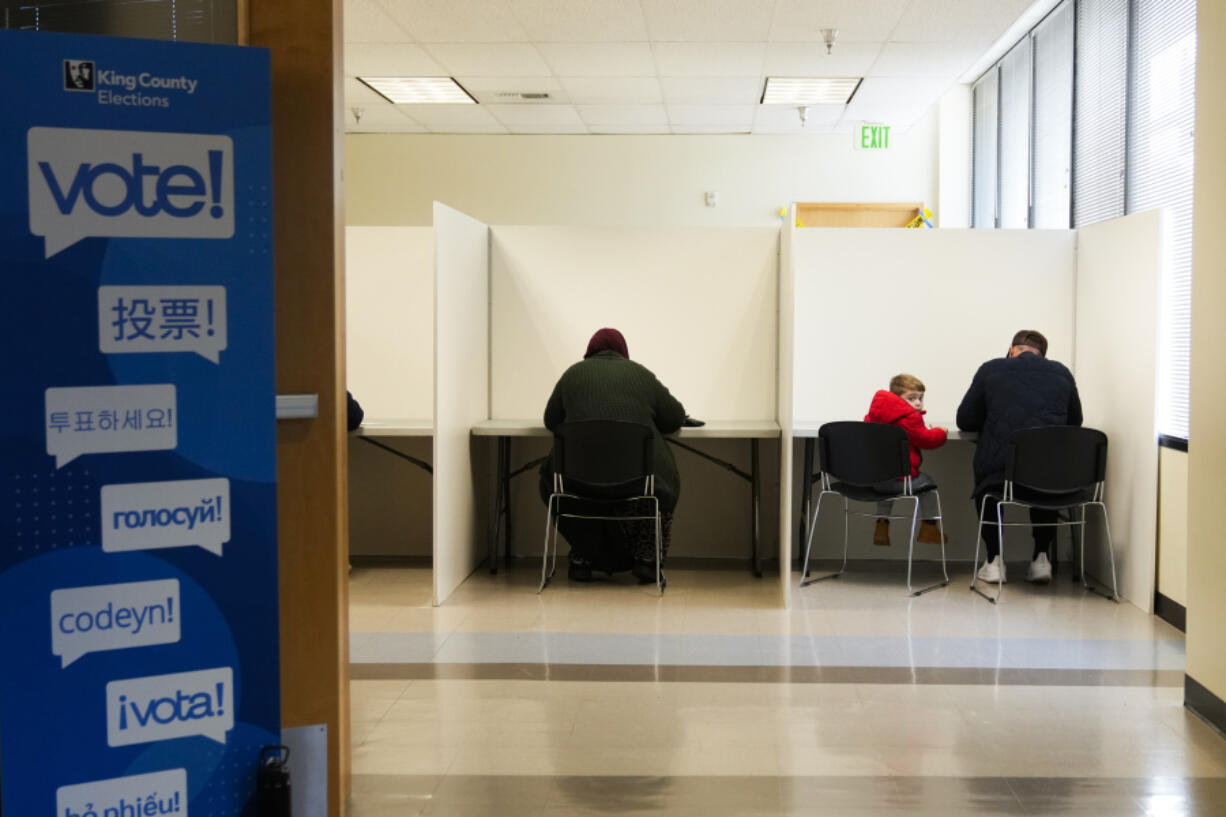 A child looks back while sitting in a voting booth at the King County Election headquarters on Election Day, Tuesday, Nov. 5, 2024, in Renton, Wash.