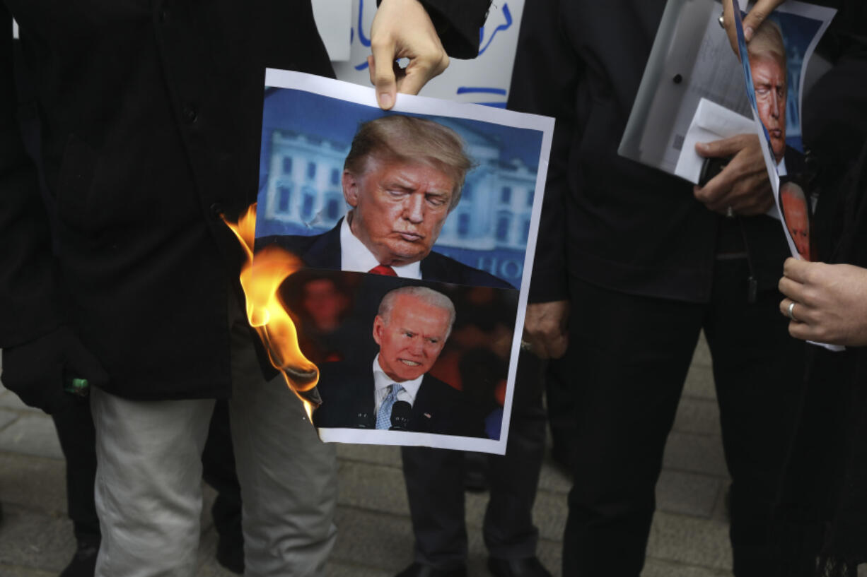 FILE &mdash; A group of protesters burn pictures of then-U.S. President Donald Trump, top, and then-President-elect Joe Biden in a gathering in front of Iranian Foreign Ministry on Saturday, Nov. 28, 2020, in Tehran, Iran.