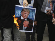 FILE &mdash; A group of protesters burn pictures of then-U.S. President Donald Trump, top, and then-President-elect Joe Biden in a gathering in front of Iranian Foreign Ministry on Saturday, Nov. 28, 2020, in Tehran, Iran.