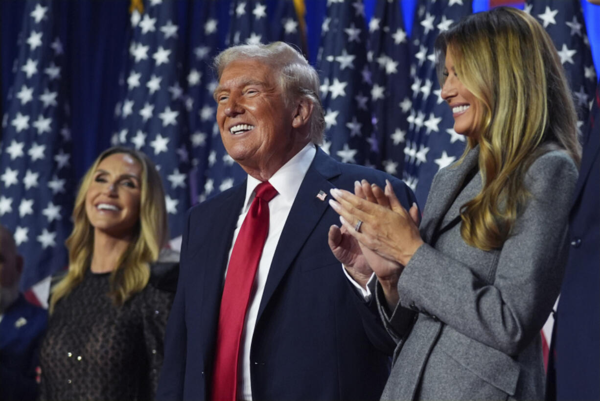 Republican presidential nominee former President Donald Trump stands on stage with former first lady Melania Trump, as Lara Trump watches, at an election night watch party at the Palm Beach Convention Center, Wednesday, Nov. 6, 2024, in West Palm Beach, Fla.