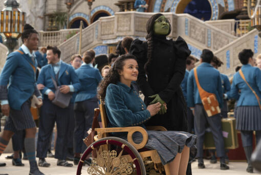 his image released by Universal Pictures shows Marissa Bode, seated center, and Cynthia Erivo in a scene from the film &ldquo;Wicked.&rdquo; (Universal Pictures via AP)