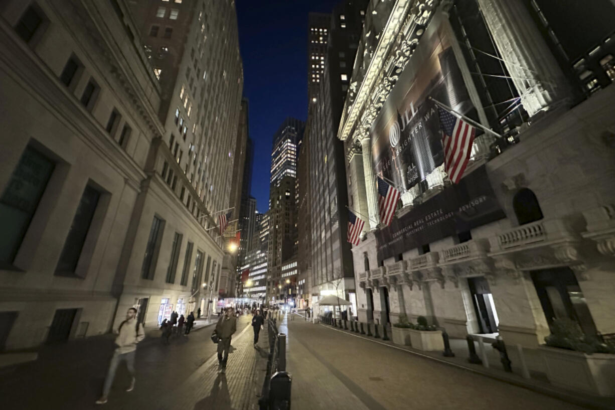 People pass the New York Stock Exchange, right, on Wednesday, Nov. 13, 2024, in New York.