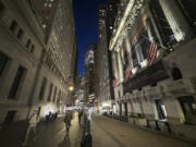 People pass the New York Stock Exchange, right, on Wednesday, Nov. 13, 2024, in New York.