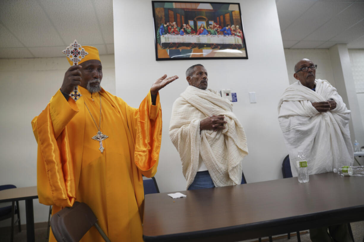 A priest, left, leads prayers at the Ethiopian Orthodox Tewahedo Church after a post-liturgy lunch on Sunday, Oct. 20, 2024, in Worthington, Minn.