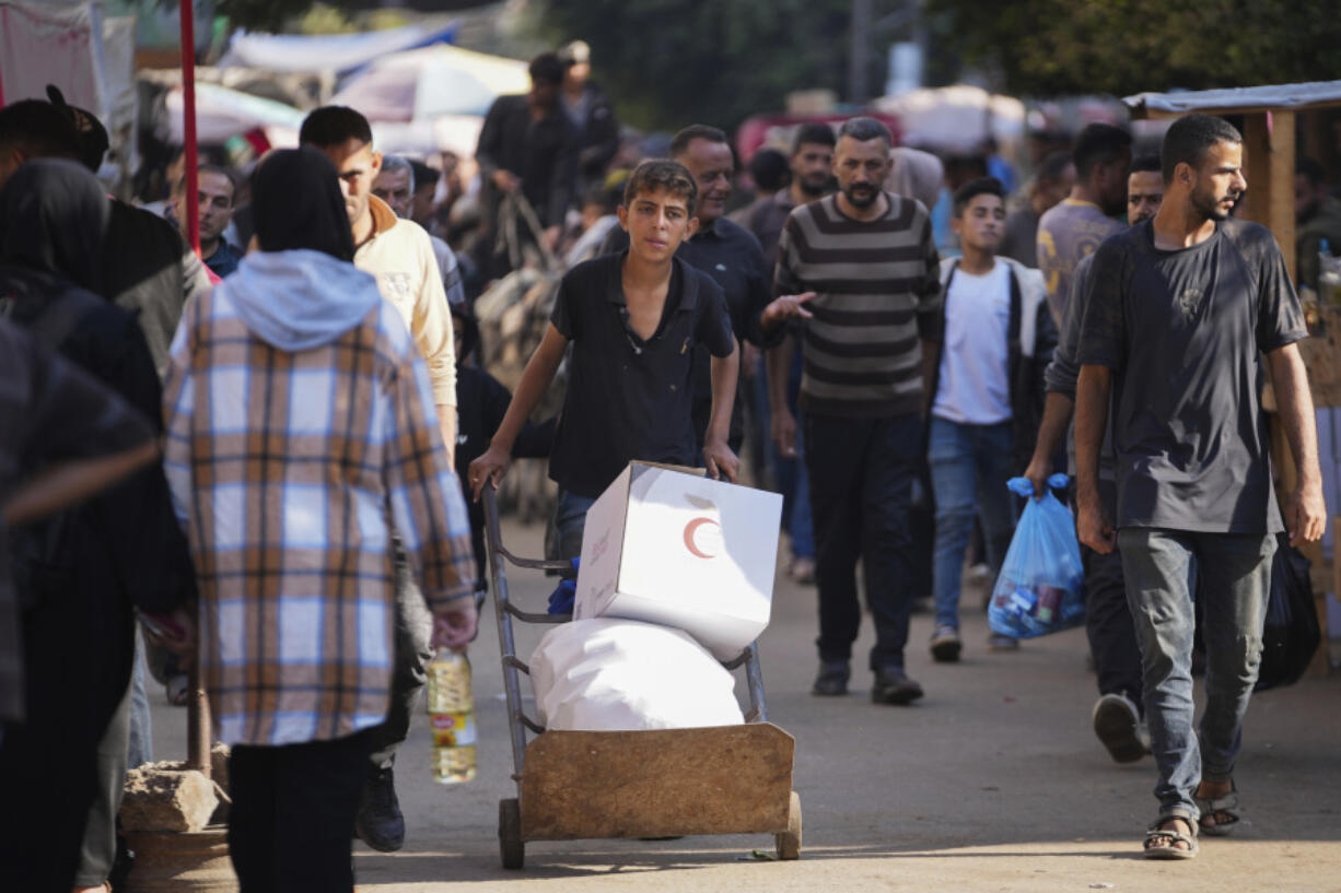 A Palestinian youth carries humanitarian aid in Deir al-Balah, Gaza, Wednesday, Nov. 13, 2024.