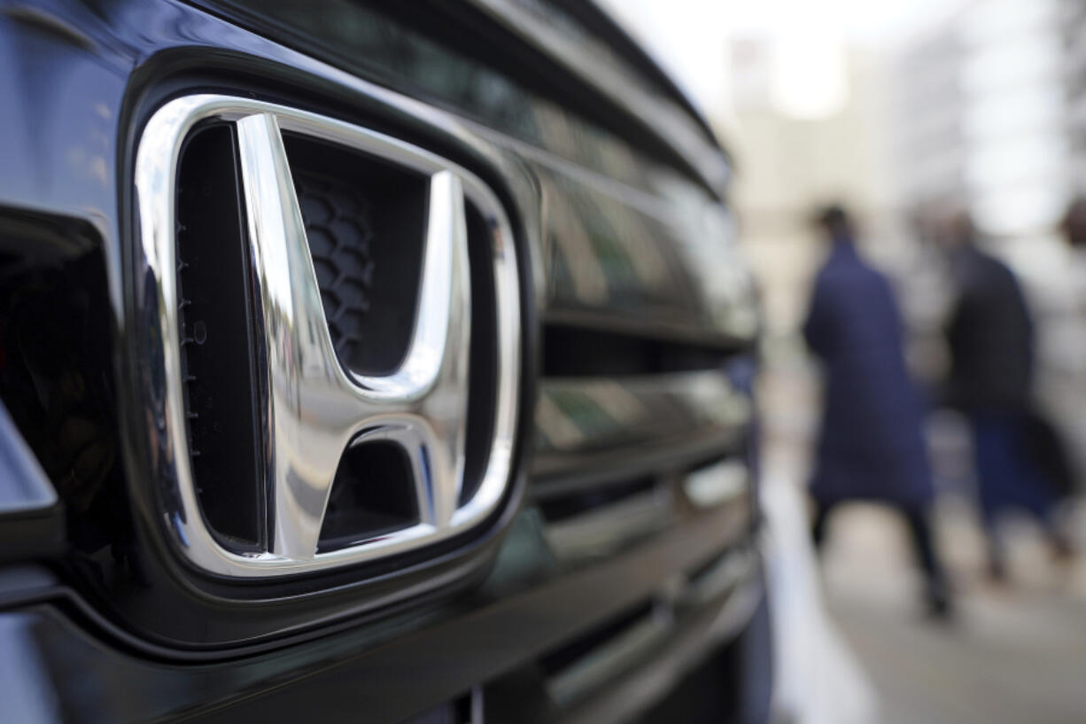 People walk near the logo of Honda Motor Company at a showroom on Feb. 8, 2022, in Tokyo.