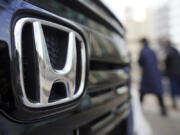 People walk near the logo of Honda Motor Company at a showroom on Feb. 8, 2022, in Tokyo.