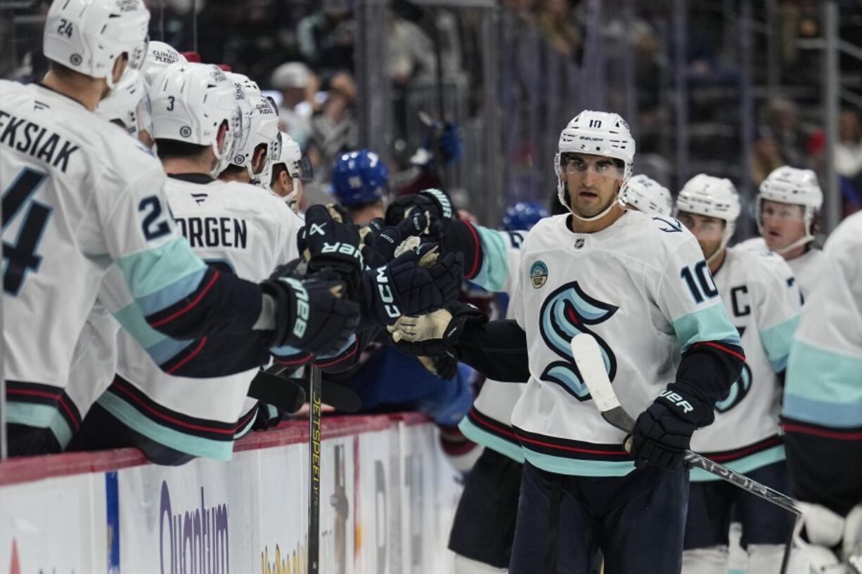 Seattle Kraken center Matty Beniers celebrates a goal against the Colorado Avalanche with teammates on the bench during the third period of an NHL hockey game Tuesday, Nov. 5, 2024, in Denver.