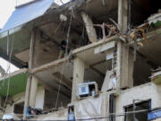 People inspect a destroyed building hit in an Israeli airstrike, in the southern port city of Sidon, Lebanon, Sunday, Nov. 3, 2024.