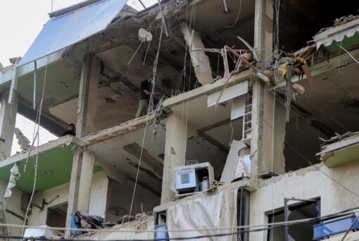 People inspect a destroyed building hit in an Israeli airstrike, in the southern port city of Sidon, Lebanon, Sunday, Nov. 3, 2024.