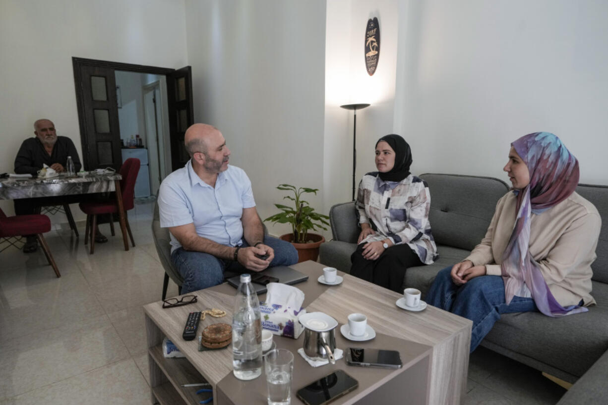 Members of a displaced family, who fled from an Israeli airstrike in Mhaibib, a Lebanese border village with Israel, share memories of their village as they sit in their house in Aramoun village, southeast of Beirut, Lebanon, Saturday, Oct. 26, 2024.