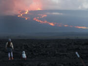 FILE - Spectators watch the lava flow down the mountain from the Mauna Loa eruption, Tuesday, Nov. 29, 2022, near Hilo, Hawaii.