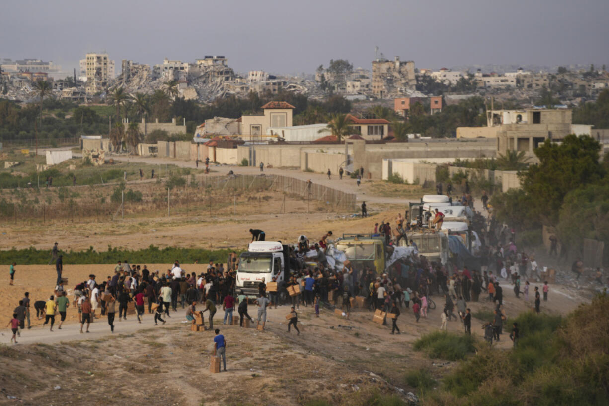 FILE - Palestinians are storming trucks loaded with humanitarian aid brought in through a new U.S.-built pier, in the central Gaza Strip, on May 18, 2024.