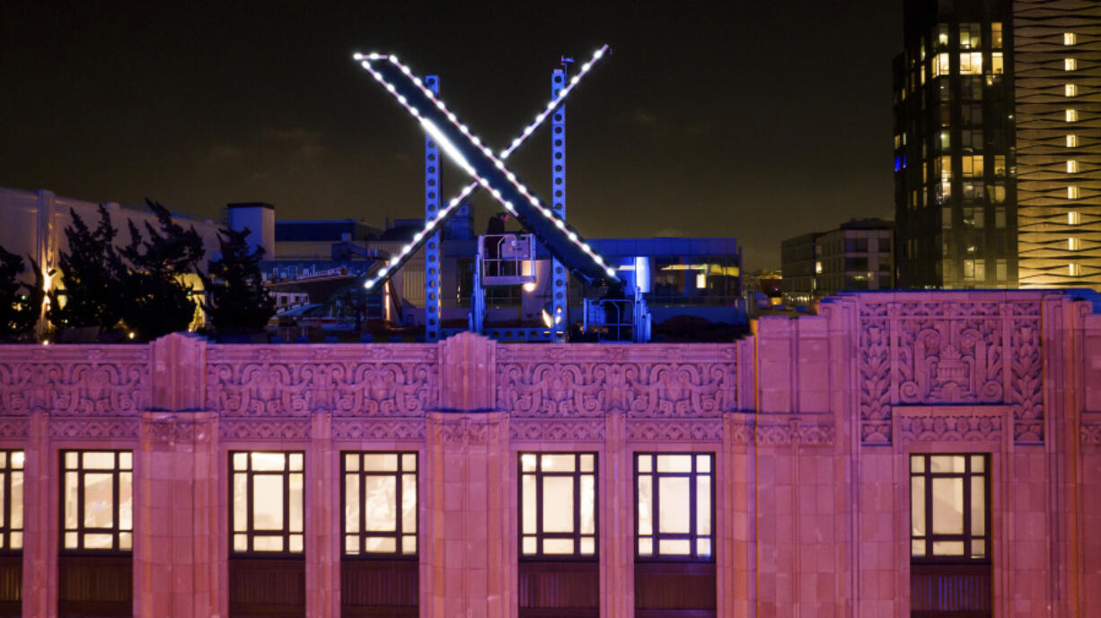 FILE - Workers install lighting on an &ldquo;X&rdquo; sign atop the company headquarters, formerly known as Twitter, in downtown San Francisco, July 28, 2023.