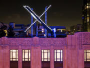 FILE - Workers install lighting on an &ldquo;X&rdquo; sign atop the company headquarters, formerly known as Twitter, in downtown San Francisco, July 28, 2023.