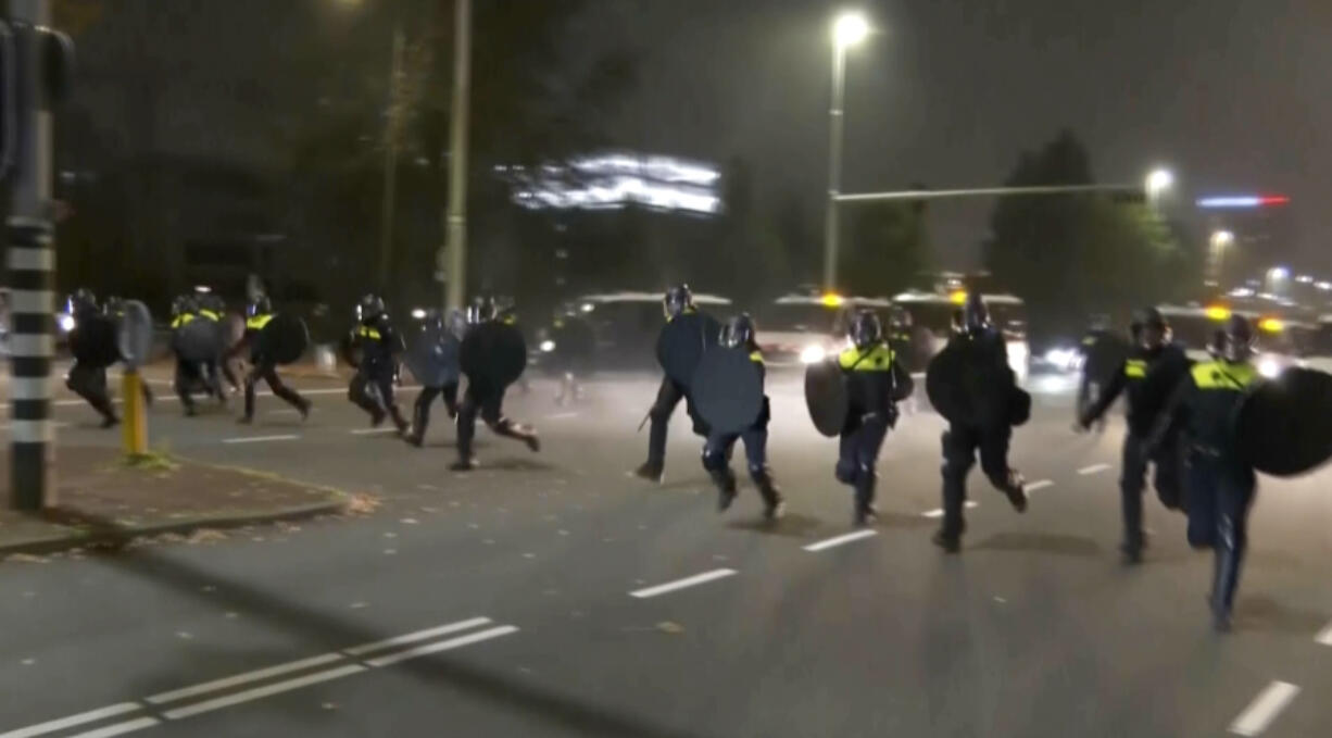 In this image taken from video, police in riot gear run towards protesters, after pro-Palestinian supporters marched near the soccer stadium, in Amsterdam, Netherlands, Thursday, Nov. 7, 2024.