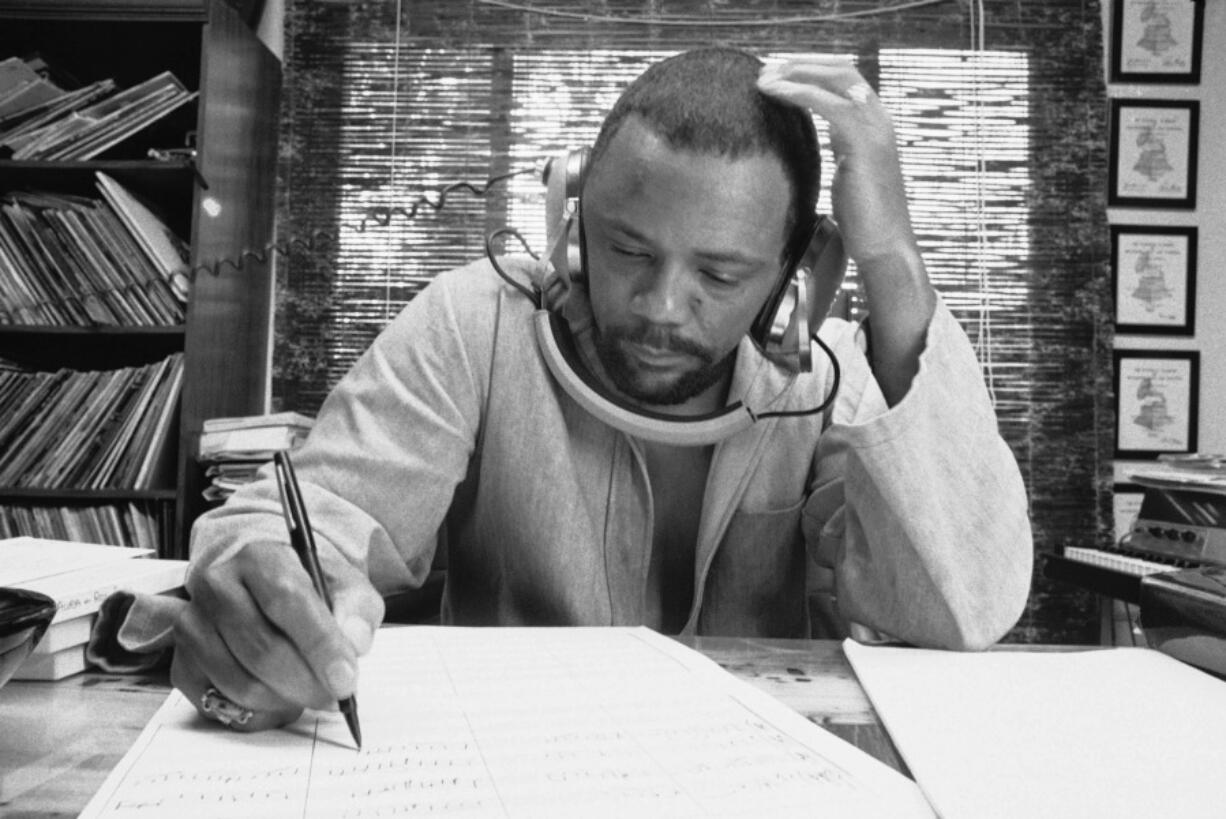 FILE - Composer Quincy Jones at his home studio in October 1974 writing music, listening to a recording on his headphones.