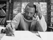 FILE - Composer Quincy Jones at his home studio in October 1974 writing music, listening to a recording on his headphones.