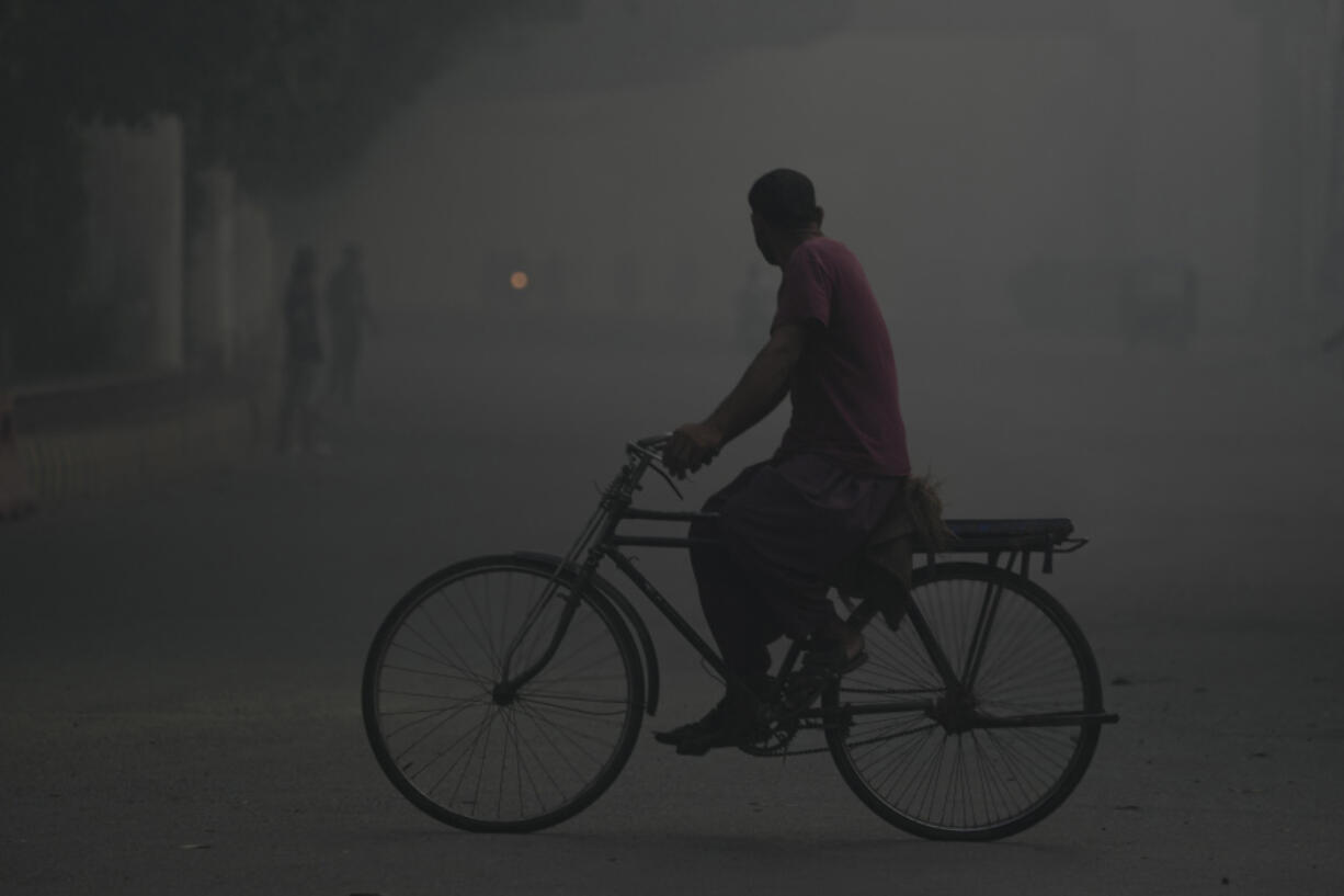 A cyclist moves during a foggy morning in Lahore, Pakistan, Sunday, Nov. 3, 2024. (AP Photo/K.M.