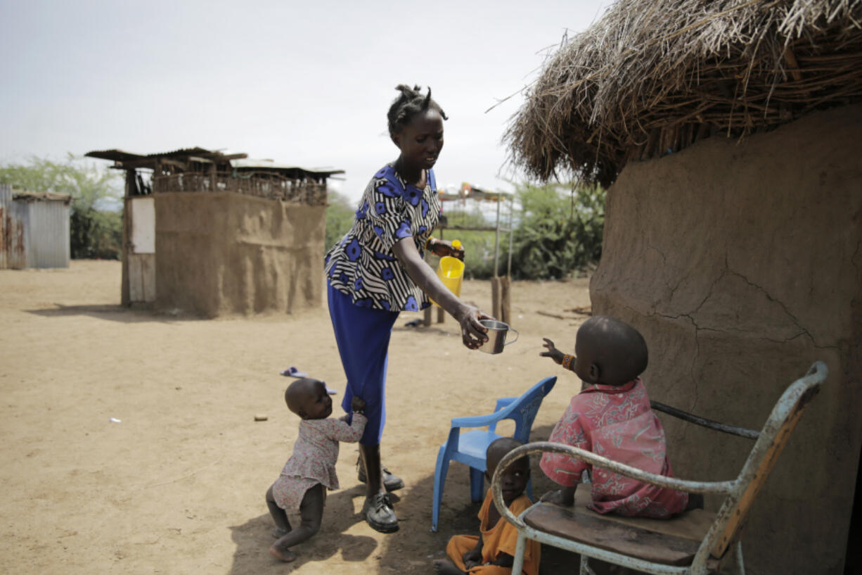 FILE - Winnie Keben gives water to her son at Meisori village in Baringo County, Kenya, July 20, 2022. Keben lost her leg to a crocodile attack, and that accident plus the loss of her home to rising water drove her and her family from their village.