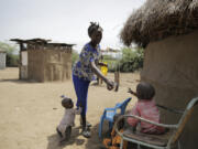 FILE - Winnie Keben gives water to her son at Meisori village in Baringo County, Kenya, July 20, 2022. Keben lost her leg to a crocodile attack, and that accident plus the loss of her home to rising water drove her and her family from their village.