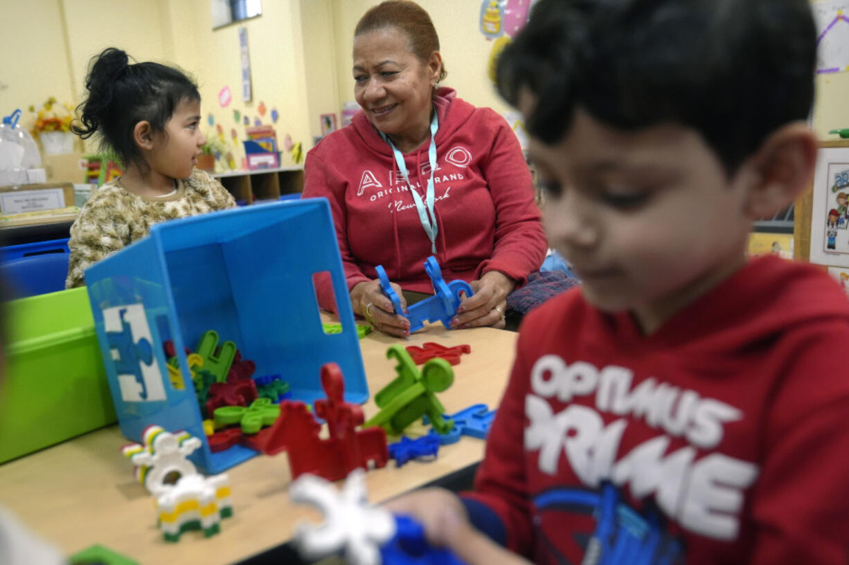 Volunteer Evangelista Baez, 72, of Providence, R.I., center, supervises three-year-olds Scarlett Mendoza, left, and Gabriel Kubbe, right, in an early childcare program at Federal Hill House, Tuesday, Nov. 12, 2024, in Providence, R.I.