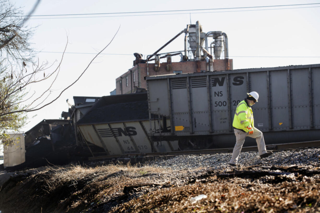 FILE - A Norfolk Southern worker walks next to the scene of a multi-car coal train derailment near Suffolk, Va., on Feb. 4, 2017.